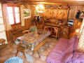 Salon du chalet individuel le Nid. Salon avec mobilier alpin rustique, grande table, canapé-lit.